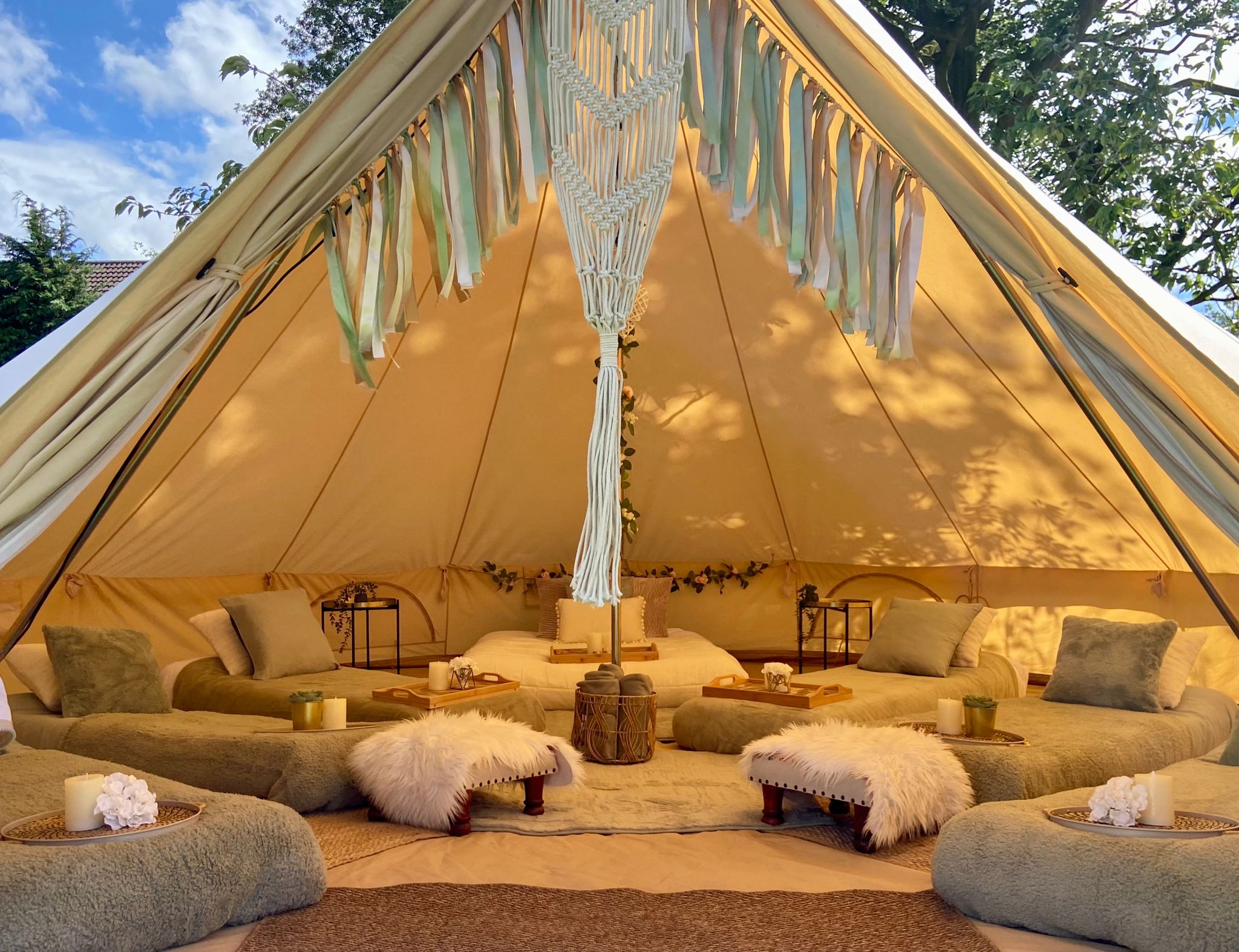 Boho-styled cream bell tent interior set up for a children's party in Cheshire, with cushions, fairy lights and a macrame hanging