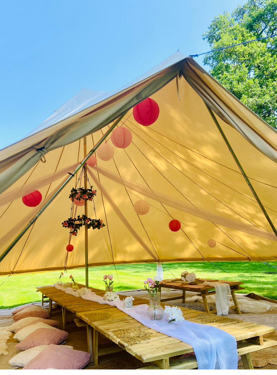 Bell tent hire Cheshire decorated with pink lanterns around a picnic-style party table
