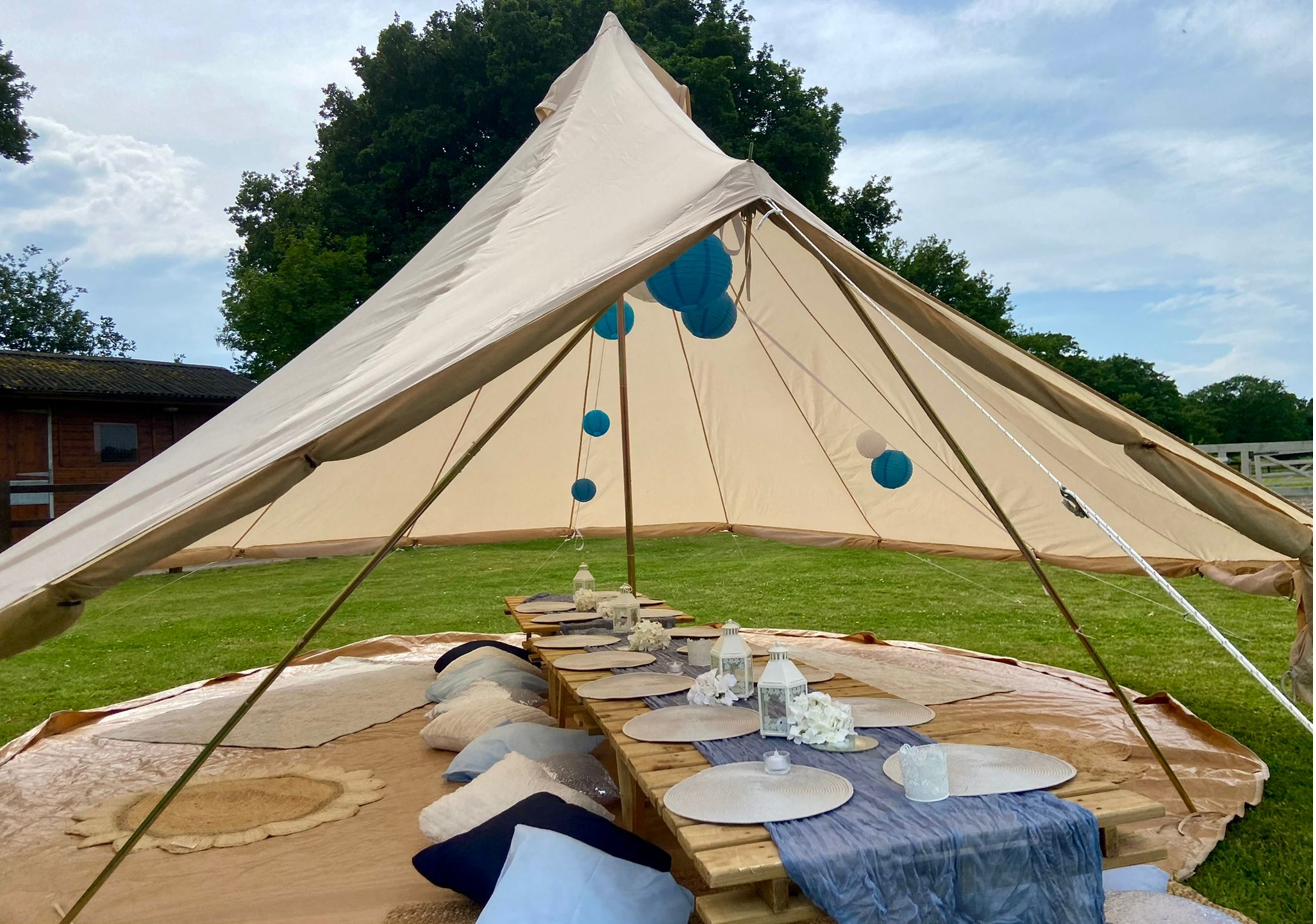 Blue themed picnic party table styled inside a bell tent with paper lanterns