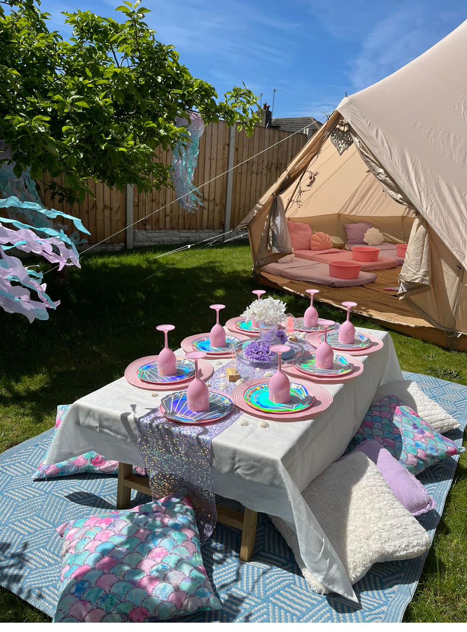 Mermaid themed picnic party table with iridescent tableware, set up inside a bell tent