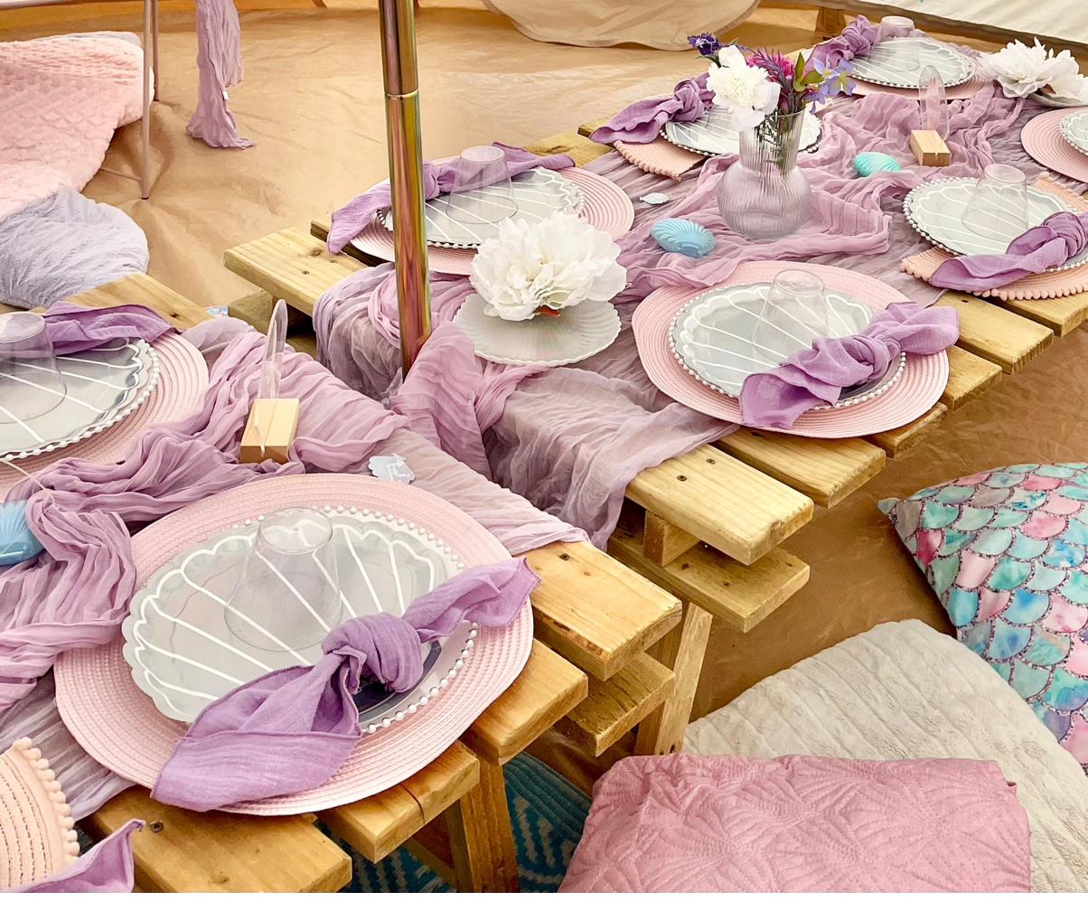 Close-up of pink and purple themed party table styling with decorative tableware